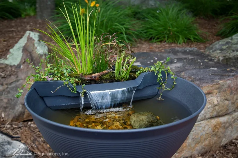 LED-lit waterfall feature in AquaGarden Mini Pond Kit for tranquil nighttime ambiance.