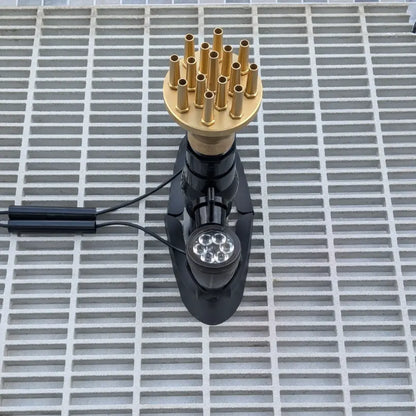 Gold column nozzle on a fountain sump pit grate with lights