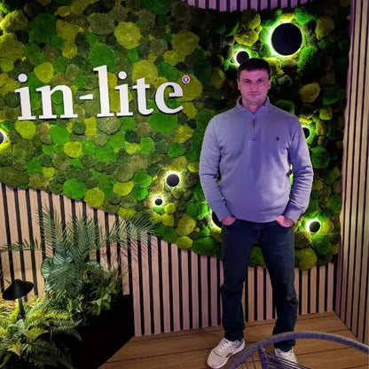 Person standing in front of a green wall with 'in-lite' branding